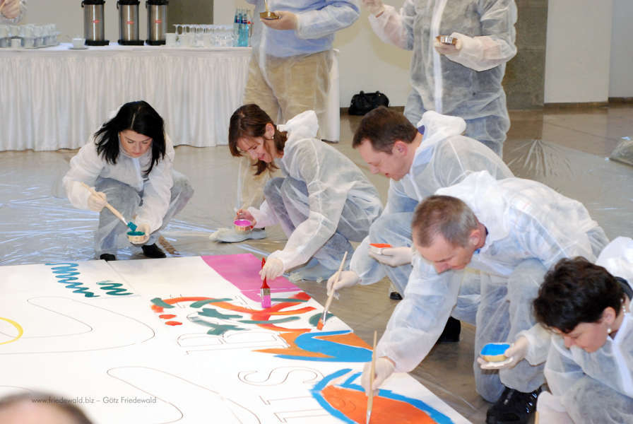 Teilnehmende spritzen Farbe auf Leinwand beim Action Painting Event